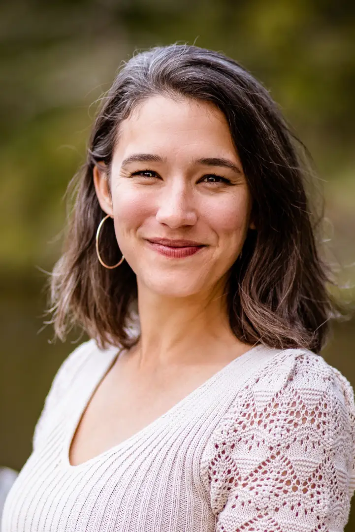 Smiling woman with medium-length hair and hoop earrings.