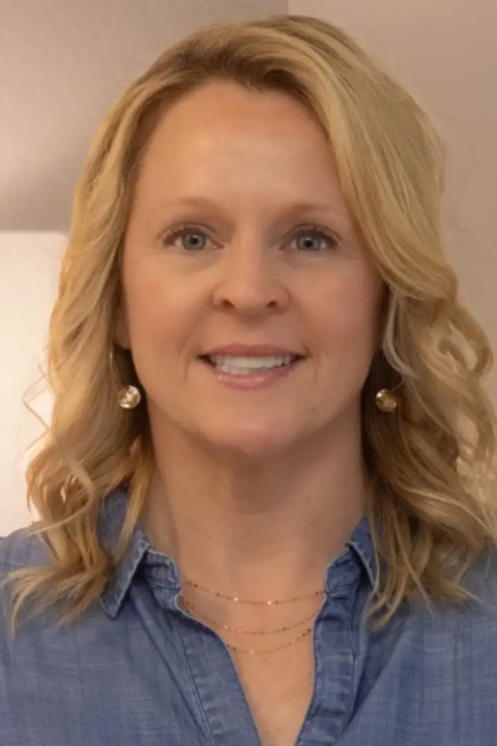 Smiling woman with blonde hair and blue shirt.