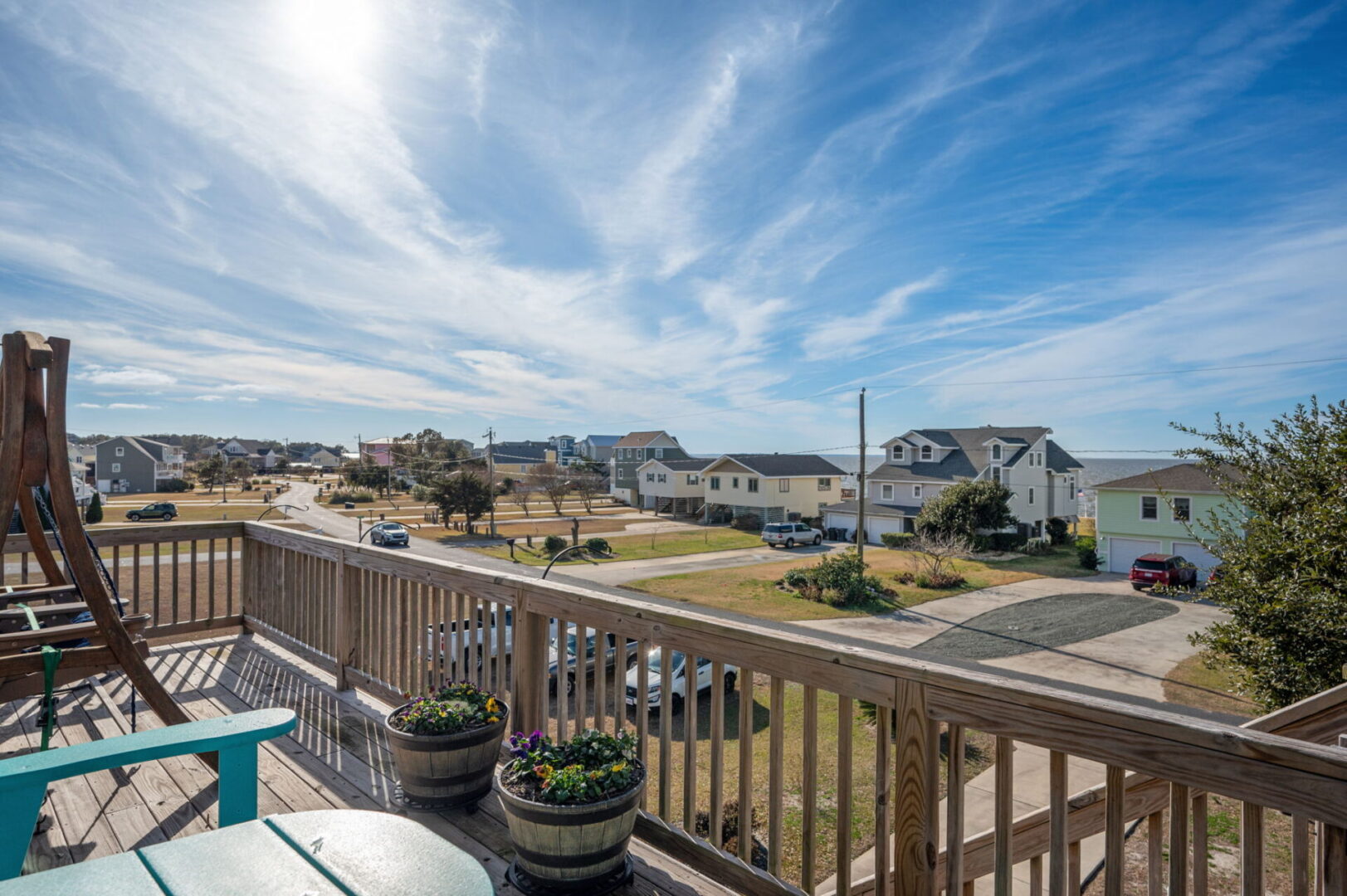 View from a wooden balcony overlooking a coastal neighborhood with blue skies.