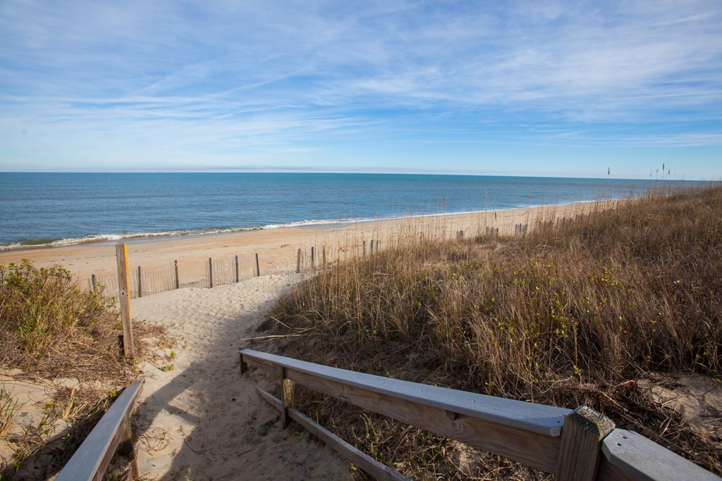 Pathway leading to a calm beach on a clear day.