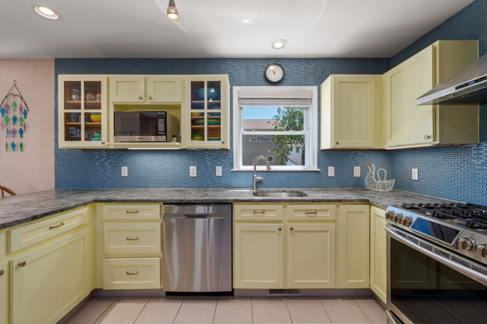 Bright kitchen with yellow cabinets and blue backsplash.